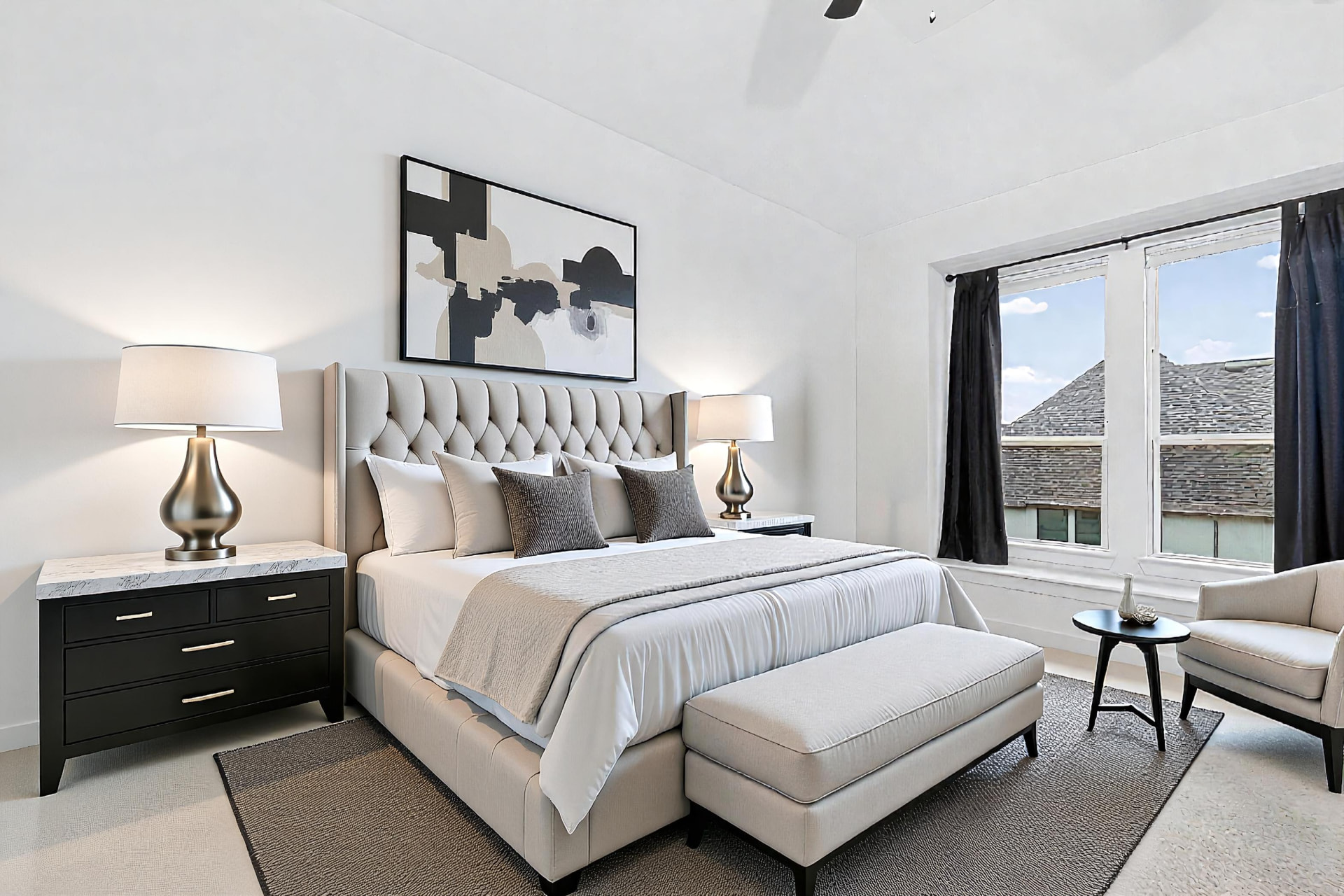Primary bedroom with an upholstered headboard, a bench at the foot of the bed, art above the bed and lamps on both nightstands.